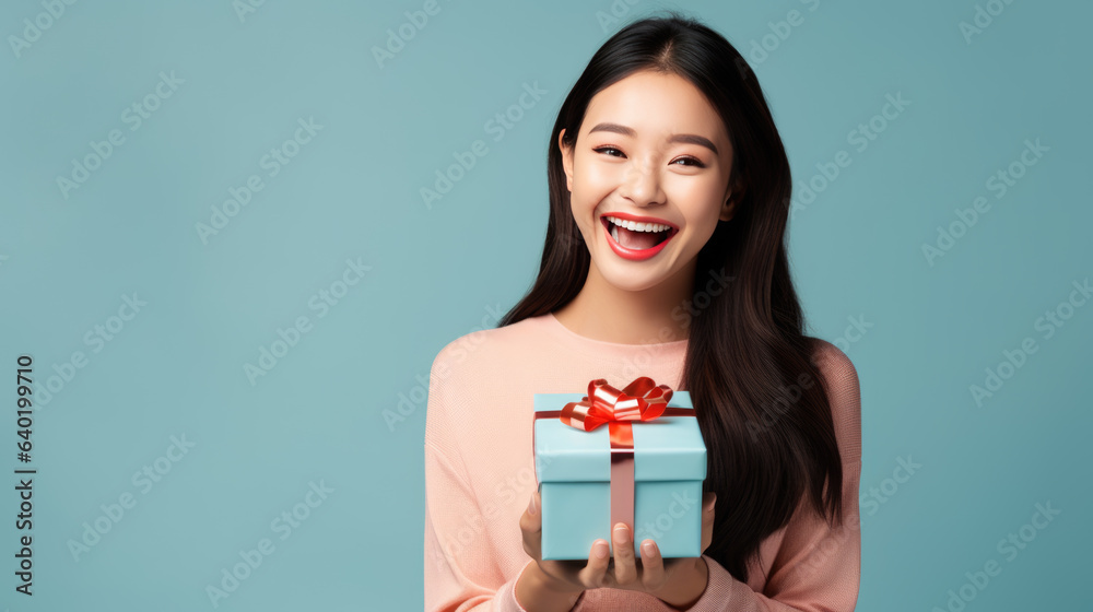Happy smiling woman holding gift box over blue background Happy smiling woman holding gift box over blue background