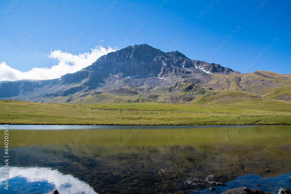 Small lake on top of a mountain. Crystal clear lake and mountain. Beautiful landscape with lake, fields and mountain