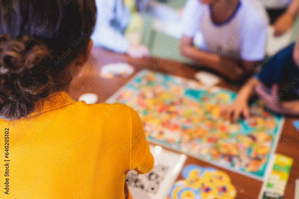 Fototapeta premium Process of playing board game and having fun with friends and family indoors, board game concept, group of kids children play board games at the table, roll the dice
