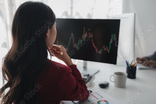 Asian woman looking at stock market graph screen, stock market businessman analyzing stock market rise and fall chart, stock market investor, profit making. investment concept.