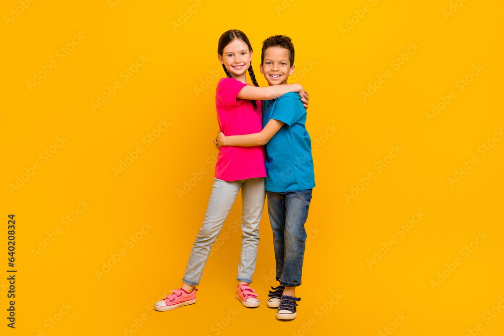 Photo of sweet pretty preteen schoolkids dressed t-shirts embracing isolated yellow color background Photo of sweet pretty preteen schoolkids dressed t-shirts embracing isolated yellow color background