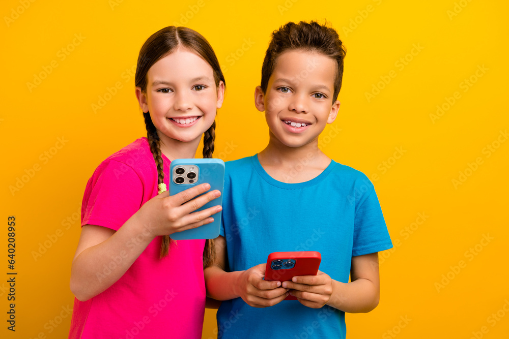 Photo of cute charming preteen schoolkids dressed t-shirts texting instagram twitter telegram facebook isolated yellow color background Photo of cute charming preteen schoolkids dressed t-shirts texting instagram twitter telegram facebook isolated yellow color background
