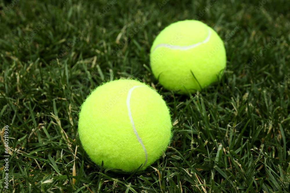 Two tennis balls on green grass, close up
