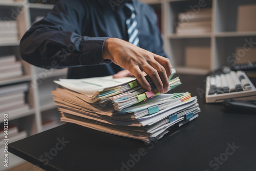 Startup company employees are rummaging through piles of paperwork for performance summaries, employees working overtime and working hard. Document management concept.