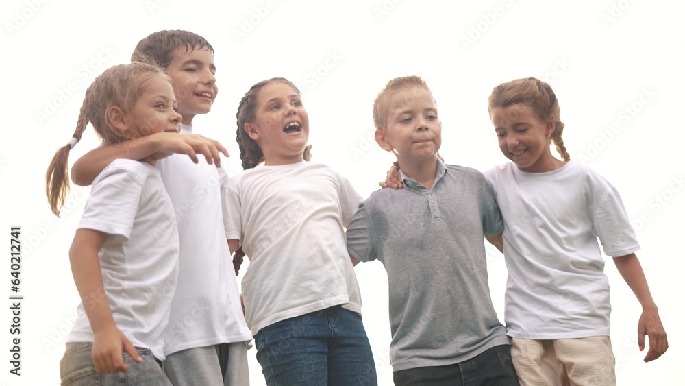 Obraz premium a group of children jumping in the park on the grass embracing. happy family childhood dream concept. little kids jump hugging each other by the shoulders. children smiling lifestyle and laughing