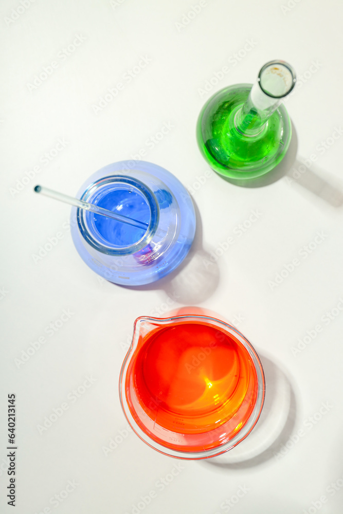 Glass flasks with colorful liquids on white background, top view Glass flasks with colorful liquids on white background, top view