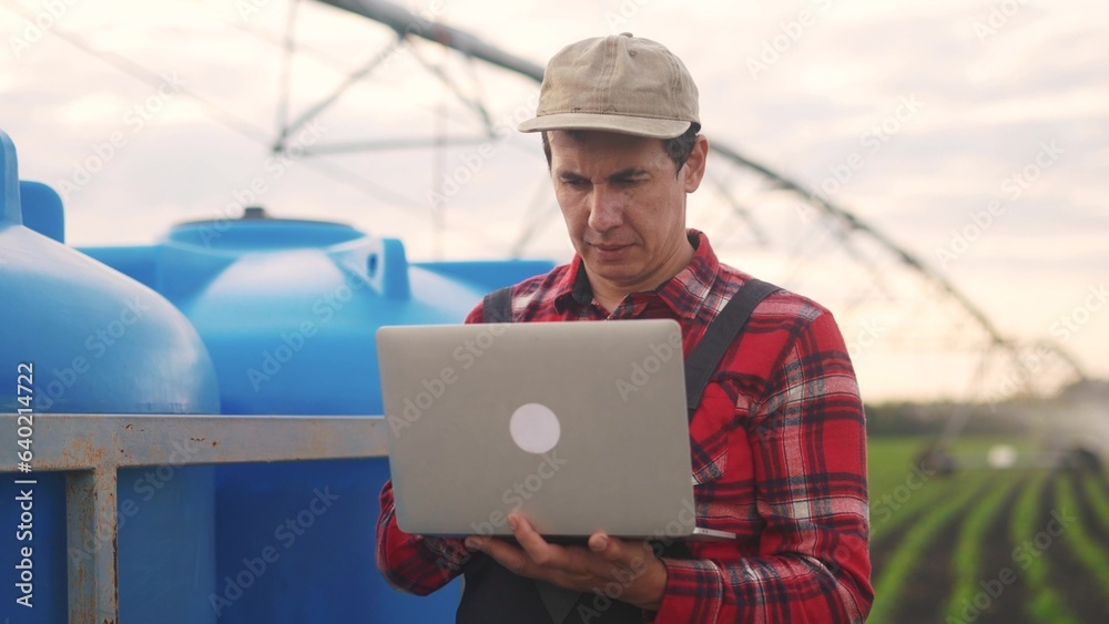 irrigation agriculture. a male farmer works on a laptop in a field with corn. irrigation agriculture business concept. farmer scientist studying corn. healthy natural foods lifestyle concept