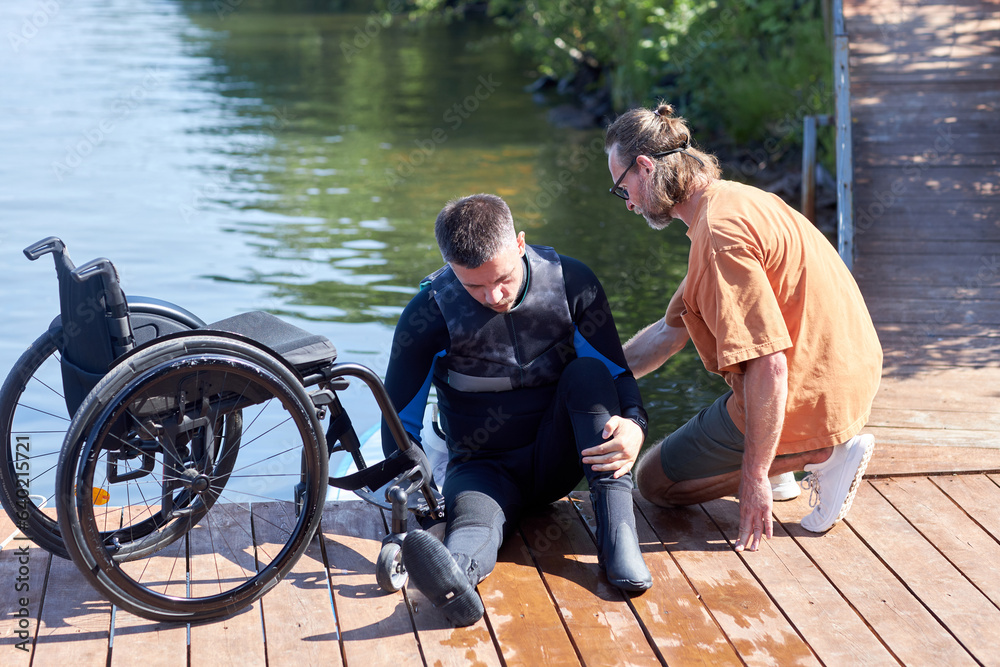 Obraz premium Full length portrait of man with disability preparing to perform water sports with adaptive equipment