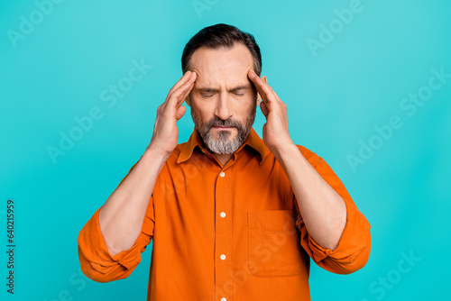 Photo of tired upset guy wear orange shirt arms head temples having headache isolated teal color background