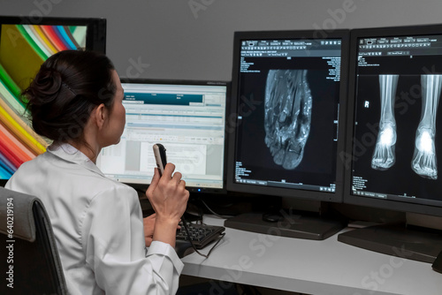 Fotomurale radiology doctor examines foot, ankle x-ray, mr image and reports with microphone looking computer screen, X-ray analysis room reading X-rays of a heel, toe and other parts of the body