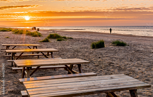 Wooden benches on sandy beach at sunset in Jurmala - famous tourist resort in...