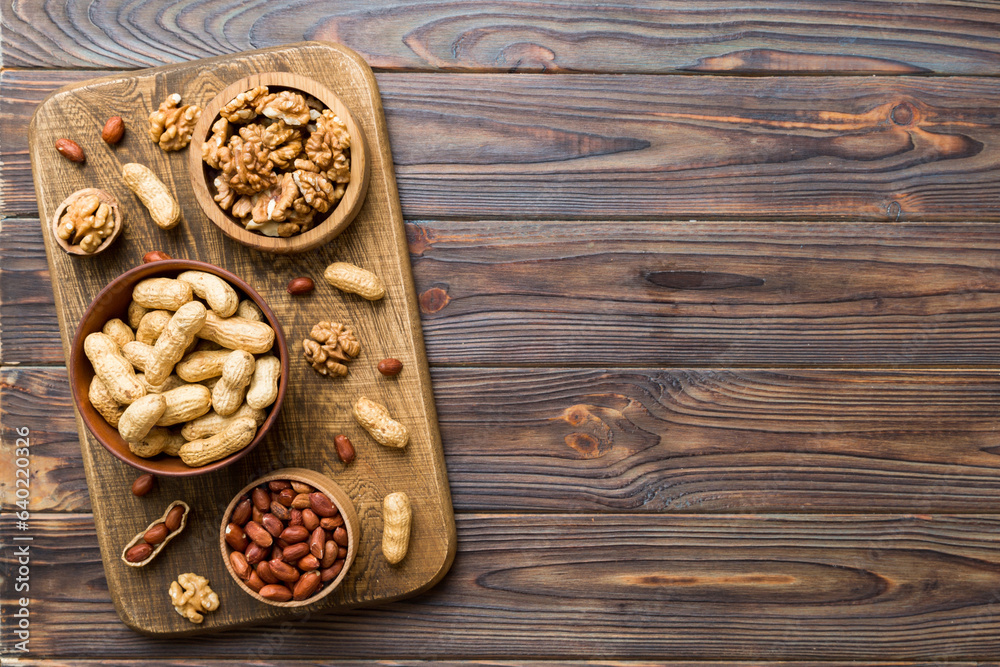 Walnut kernel halves with peanut, in a wooden bowl. Close-up, from above on colored background. Healthy eating groundnut concept. Super foods with copy space Walnut kernel halves with peanut, in a wooden bowl. Close-up, from above on colored background. Healthy eating groundnut concept. Super foods with copy space
