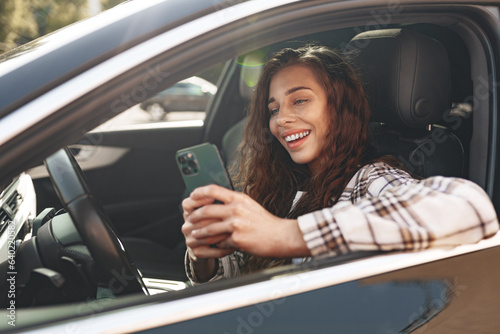 Young woman texting on her smartphone while driving a car