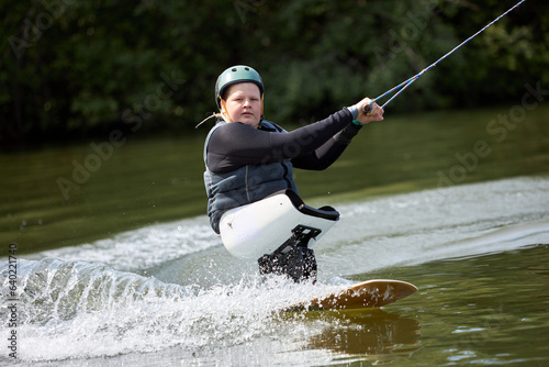 Canvas Print Action portrait of young man with disability enjoying fast speed wakeboarding on