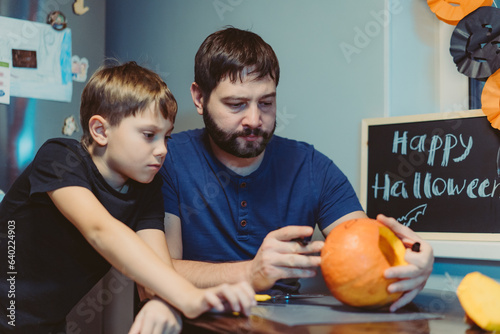 Children with father carving a traditional Jack lantern from pumpkin