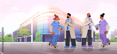 doctors with stethoscopes walking near hospital building medical workers team in uniform happy labor day celebration concept