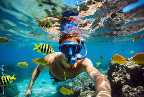 Man snorkeling in the tropical water with colorful fishes and corals. Shallow field of view photo