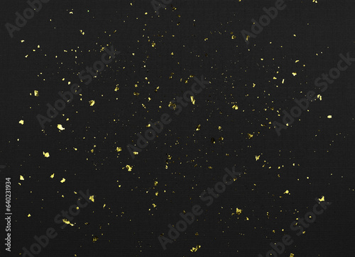 Gold flakes of potal on black textured paper photo