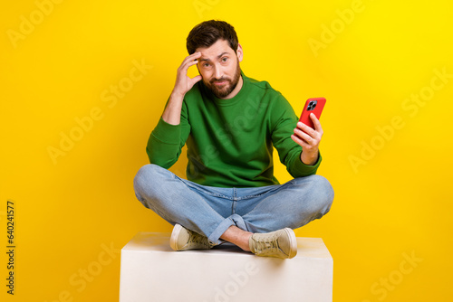 Full length body photo of stressed young man blogger think his future lost access account with phone isolated on yellow color background © deagreez