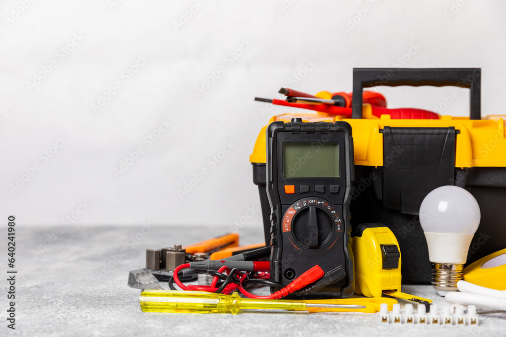 Obraz premium Electrician equipment on marble background with copy space.Top view.Electrician tool set.Multimeter, tester,screwdrivers,cutters,duct tape,lamps,tape measure and wires.Flet lay. Construction concept.