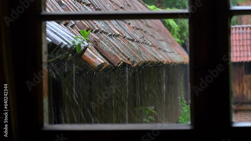 Heavy Rain Hitting Old House Roof Tiles during Thunderstorm Seen via Window