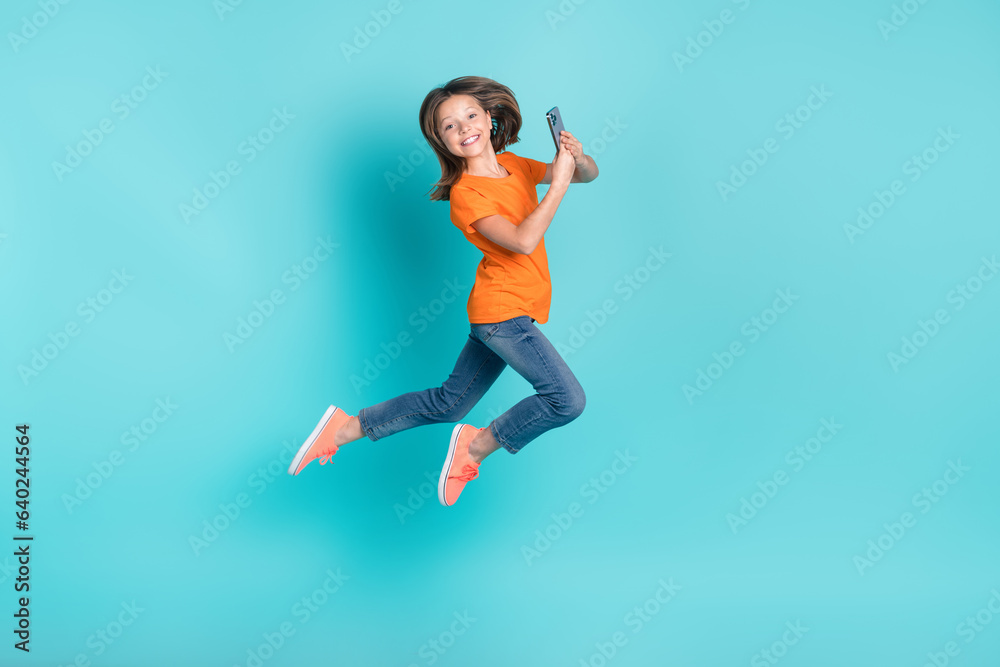 Photo of optimistic crazy girl wear trendy orange outfit hurry store mall buy modern device isolated on cyan color background