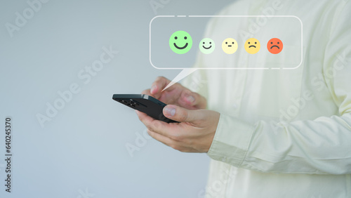 Client hands using a mobile phone with pop up smile face icon for feedback review satisfaction service opinion and testimonial. Customer service experience assessment and business satisfaction survey.