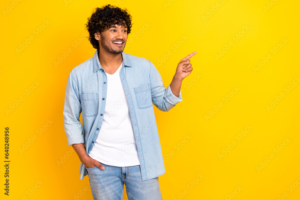 Photo of charming dreamy guy dressed denim jacket looking showing finger empty space isolated yellow color background Photo of charming dreamy guy dressed denim jacket looking showing finger empty space isolated yellow color background