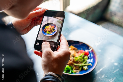 hand with smartphone photographing food at restaurant or cafe photo