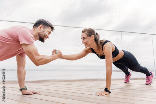 Confident, strong people in sportswear. A couple of friends are using a fitness watch and a sports app.  A man and a woman train together. The trainer and the client teach fitness exercises.