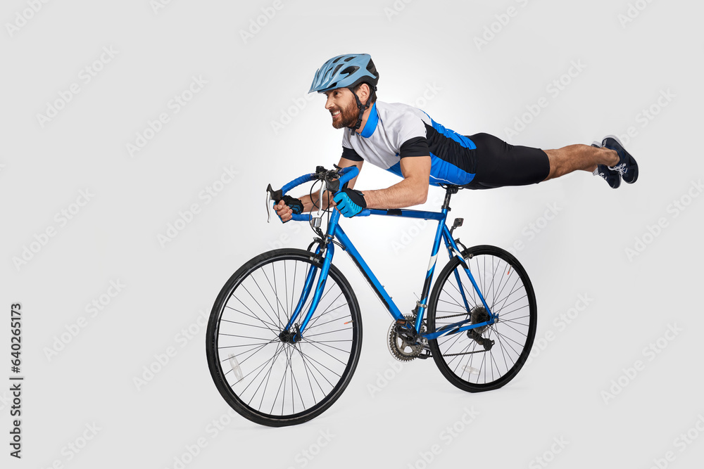 Strong middle aged cyclist doing trick on bike, while riding. Side view of caucasian male rider cyclist showing acrobatic stunt, isolated on white background. Cycling skills, sport activity concept. Strong middle aged cyclist doing trick on bike, while riding. Side view of caucasian male rider cyclist showing acrobatic stunt, isolated on white background. Cycling skills, sport activity concept.