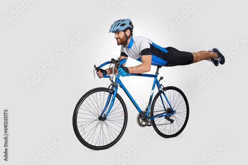 Fototapeta Naklejka Na Ścianę i Meble -  Strong middle aged cyclist doing trick on bike, while riding. Side view of caucasian male rider cyclist showing acrobatic stunt, isolated on white background. Cycling skills, sport activity concept.