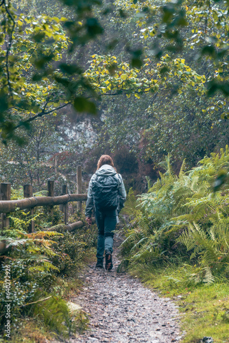 A young girl walking alone in the forest path and enjoy the rain.