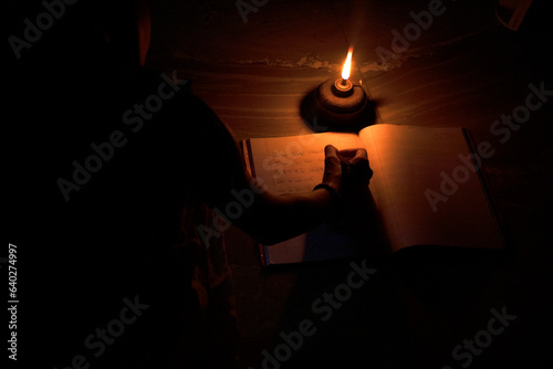 Student in rural village studying in oil lamp
