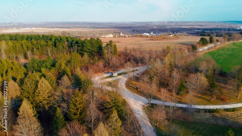 Aerial view along road between the fields and golden fall forest of north america. Farming  fields with harvest  north american golden fall forest is best tourist place in fall to camping and photo.