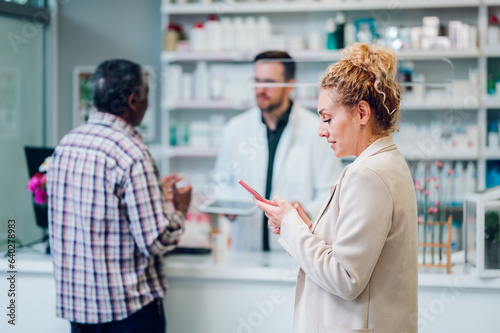 Portrait of a woman patient in a pharmacy using a smartphone