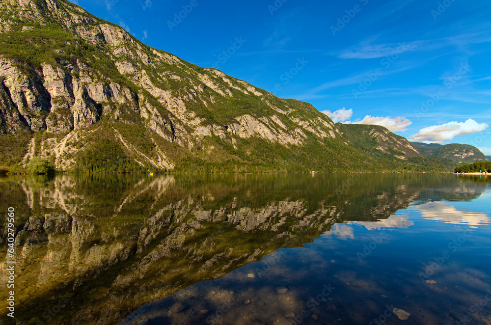 Astonishing panoramic nature landscape of scenic mountain range which reflected in turquoise water of Bohinj Lake, Triglav National Park, Slovenia. Concept of landscape and nature
