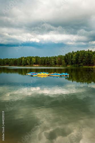 A group of empty yellow and blue pedal boats in the middle of a lake. Majdan Sopocki, Roztocze, Poland photo