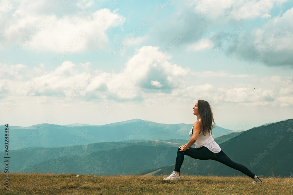 Yoga and meditation program in nature. A beautiful young woman in a beautiful mountain landscape, with a cloudy sky.