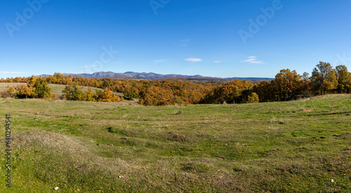 Panoramic view of landscape with meadows, forests and mountains in the background