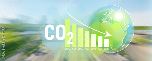 Decreasing arrow graph, planet Earth drawing. The concept of reduce co2 emission, motion blur of panoramic cityscape on the background.