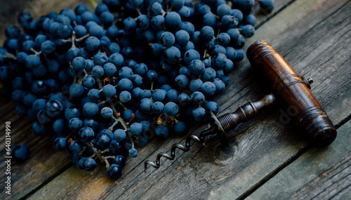 vintage corkscrew with ripe grapes lay on a rustic wood table. Concept of autumn, vineyards, winemaking,