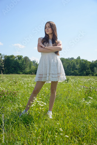 Beautiful young woman in a flowery meadow in a white dress