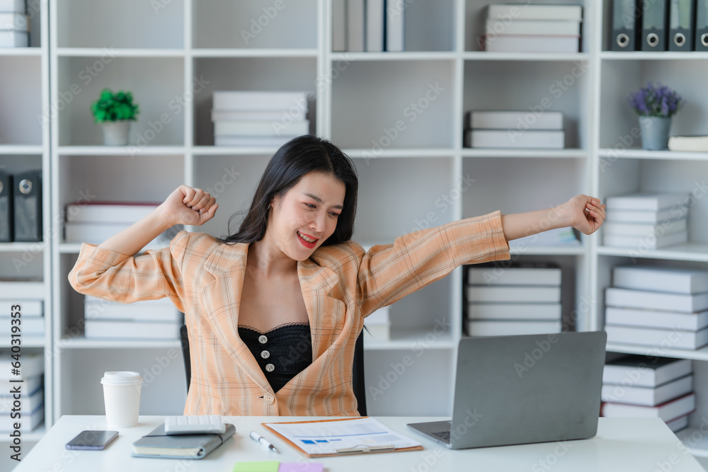 Obraz premium Cheerful business lady working on laptop in office, Asian happy beautiful businesswoman in formal suit work in workplace. Attractive female employee office worker smile.