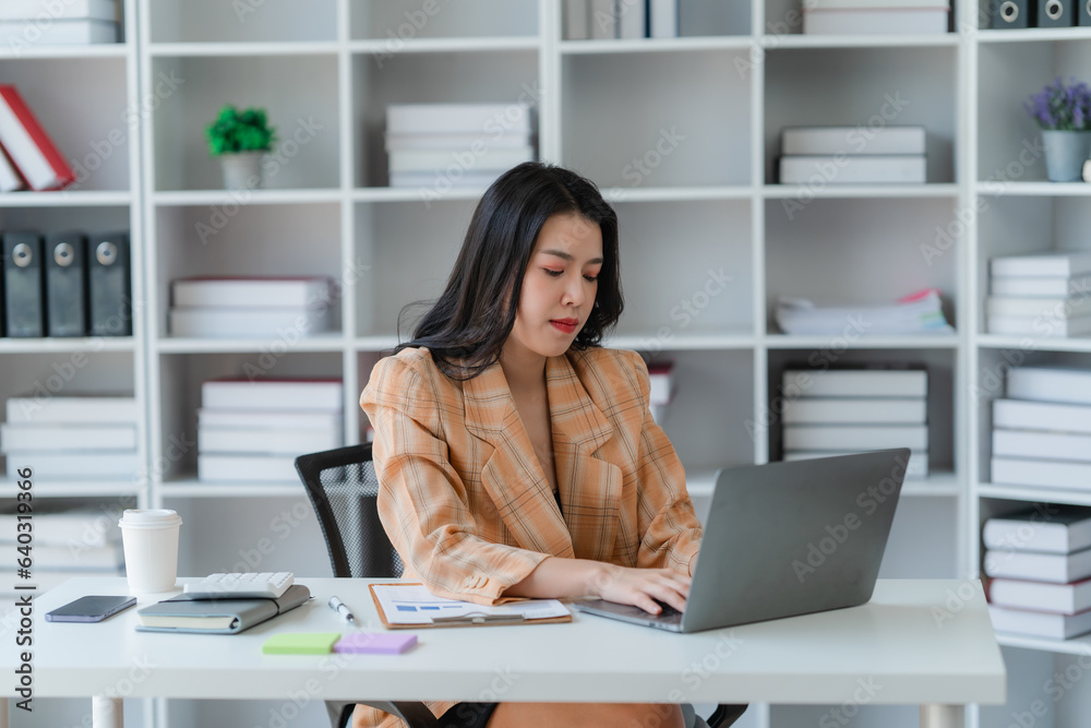 Asian woman working through laptop. business woman busy working with laptop computer at office Asian woman working through laptop. business woman busy working with laptop computer at office