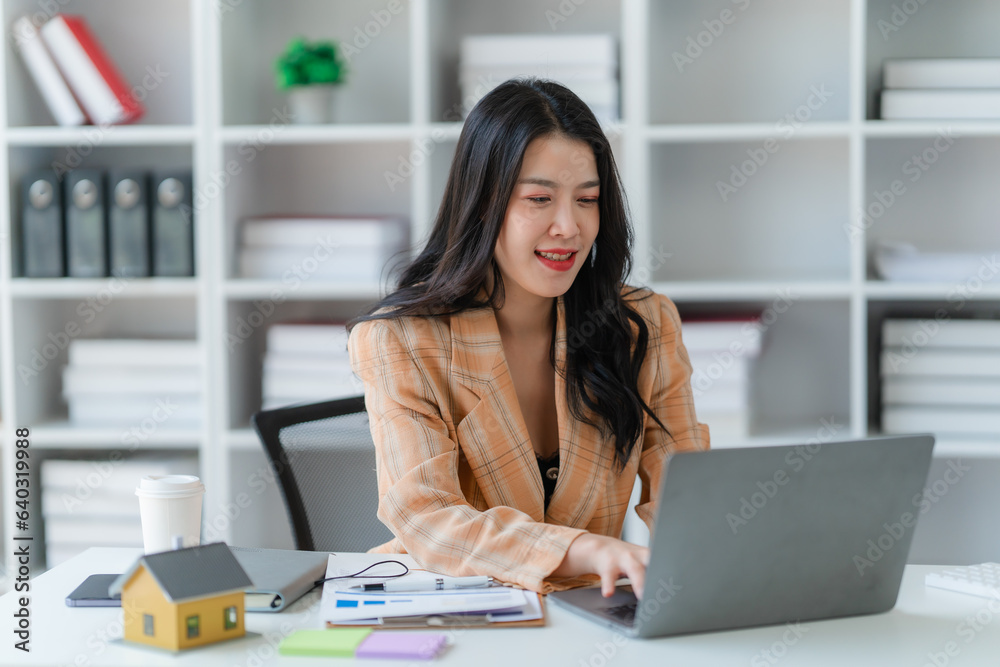 Asian woman sitting at a desk working in the office use a computer, laptop Asian woman sitting at a desk working in the office use a computer, laptop