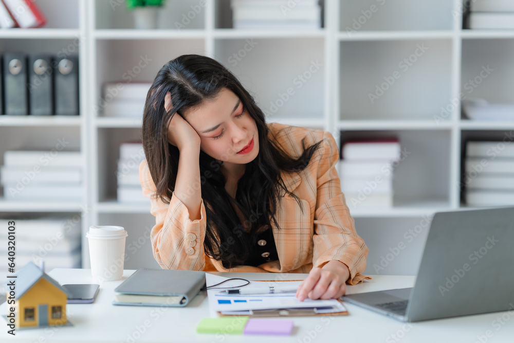 Fototapeta premium tired business woman sleepy and bored from sitting at a desk for a long time and has office syndrome