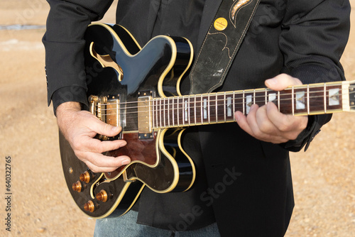 Macro of guitar player holding guitar.