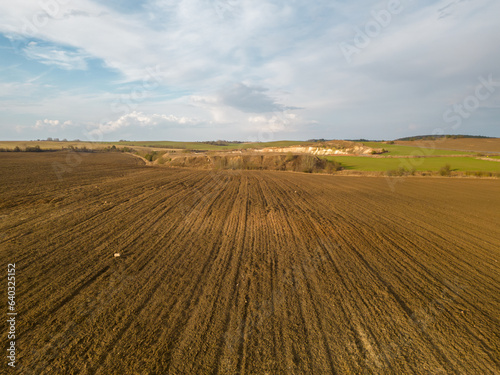 Drone photo of a plowed fields at sunset. Aerial view of a farmer's field. Abstract patterns and straight lines on agricultural land.