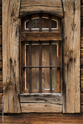 Stare drewniane okno z metalowymi, zardzewiałymi kratami.
